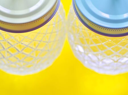 Two glass jars, pineapple shaped, against yellow background, natural light, selective focus.の写真素材