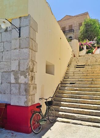 Green bicycle against wall, in front of staircase at Symi island, Greece, sunny summer day.の写真素材
