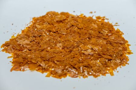 Shellac flakes, shellac is a  resin secreted by the female lac bug. It is dissolved in alcohol to make liquid shellac, which is used as a brush-on colorant, food glaze and wood finish.の写真素材