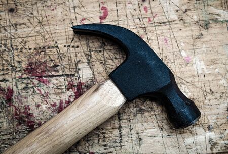 Iron claw hammer with wooden handle on used grunge stained wooden bench surface.の写真素材