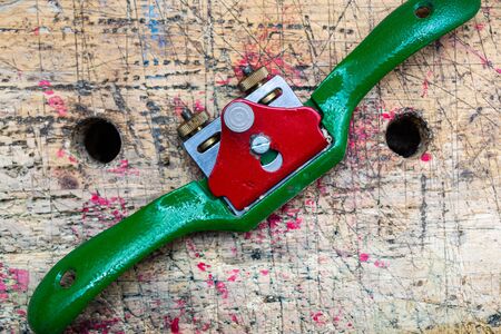 Carpenter spokeshave , metal hand woodworking tool isolated on wooden workbench stained grunge textured surface with holes.の写真素材