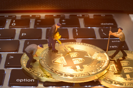 Miniature figure people working on Cryptocurrency golden bitcoin, on laptop keyboard, Conceptual image for worldwide crypto currency, huge stack physical version of golden Bitcoin.の写真素材