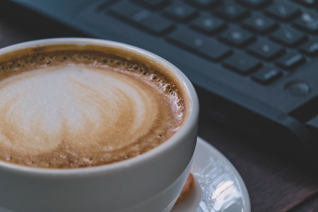 Cup of coffee with beautiful latte art  on wood tableの写真素材