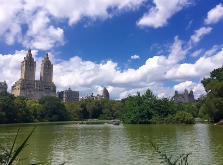 Lake, buildings and boats with clouded blue sky at Central Park, Manhattan, New Yorkの写真素材