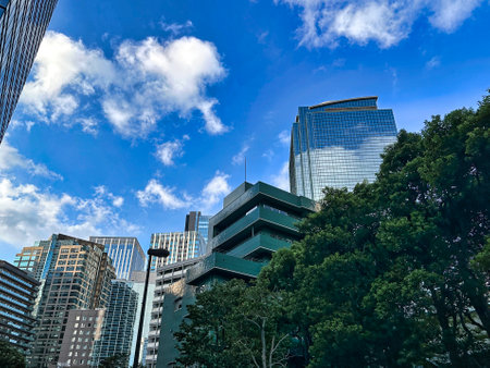 Urban high-rise apartment building with blue sky, white clouds and green plants, daytimeの写真素材