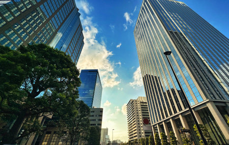 Urban high-rise apartment building with blue sky, white clouds and green plants, daytimeの写真素材