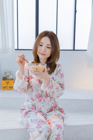 Lady in nightwear eating cerealsの写真素材