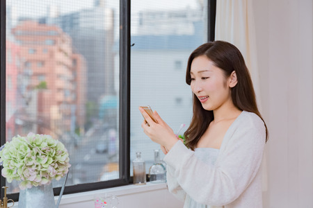 Lady looking at mobile smartphone brushing teethの写真素材