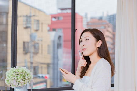 Lady looking at mobile smartphone brushing teethの写真素材