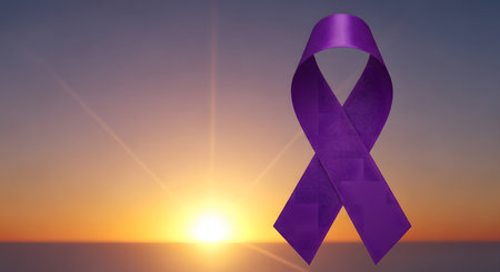 A textured purple awareness ribbon stands prominently against a vibrant sunrise, casting warm light and symbolizing hope, support, and the ongoing fight against various diseases and causes.の写真素材