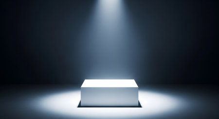 White cube illuminated by a spotlight in a dark room with copy spaceの素材