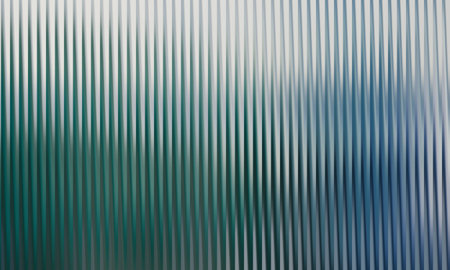 A textured surface of corrugated glass with green and blue hues provides an abstract background. The light and shadow create a visually interesting effect.の写真素材