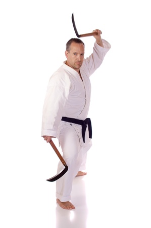 Man in karate-gi holding a pair of kamaの写真素材