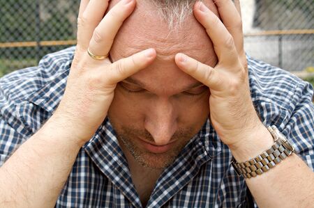 Man with his hands in his face looking tiredの写真素材
