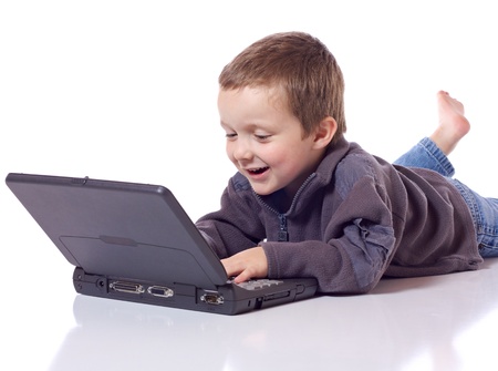 Cute little boy laying on his stomach with a laptopの写真素材