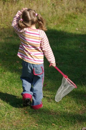 Little girl hunting butterflies with a net in a trail in the woodsの写真素材