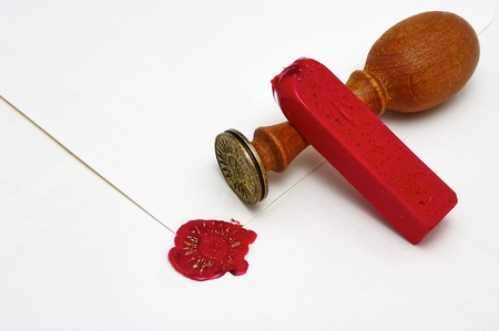 Signet stamped in red wax and gold ink to seal a parchment envelope