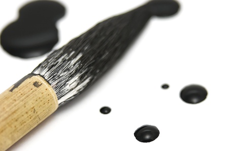 Black chinese ink dots with a calligraphy brush resting nearby. This is a close macro shot with very low depth of field.の写真素材