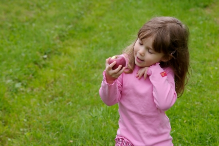 Little girl dressed in pink and picking apples in an appletreeの写真素材