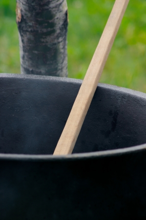Old pot with a spoon over a fireの写真素材