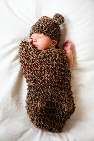 Newborn baby boy resting in a wool cocoon