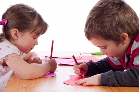 Cute little girl drawing on a pink heartの写真素材