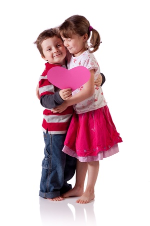 Cute little children hugging and holding a pink heartの写真素材