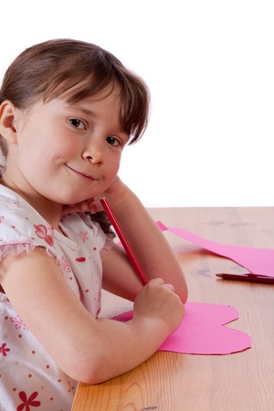 Cute little girl drawing on a pink heartの写真素材