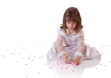 Cute little girl sitting on the floor with heart shaped confettiの写真素材