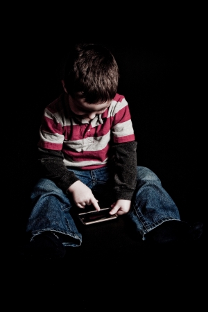 Cute little boy holding a portable video gameの写真素材