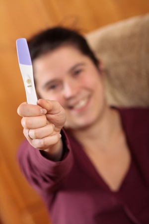 Happy woman holding a positive pregnancy testの写真素材