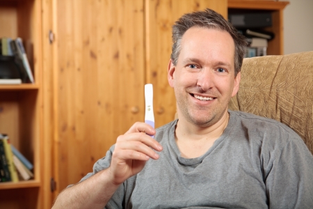 Happy man holding a positive pregnancy testの写真素材