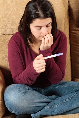 Worried woman holding a pregnancy testの写真素材
