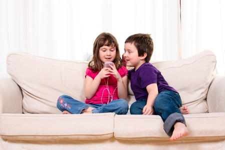 Children listening to music while sitting on a couchの写真素材