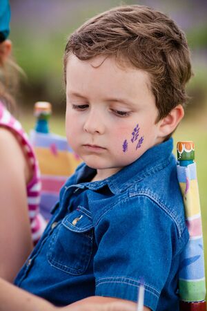 Cute little boy getting make-up on his face