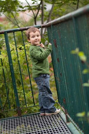 Young boy smiling by a metal fenceの写真素材