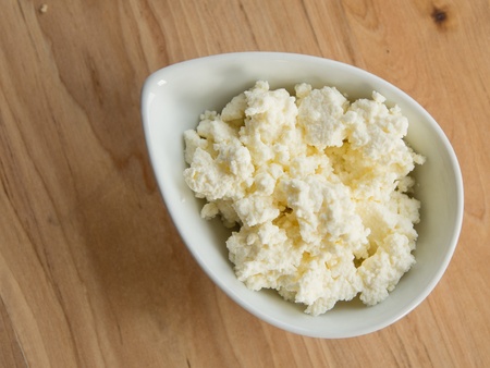 Homemade cottage cheese in a bowl on a cutting boardの写真素材