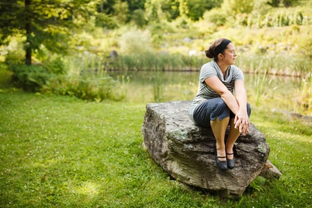 Woman sitting on a rock by a pondの写真素材