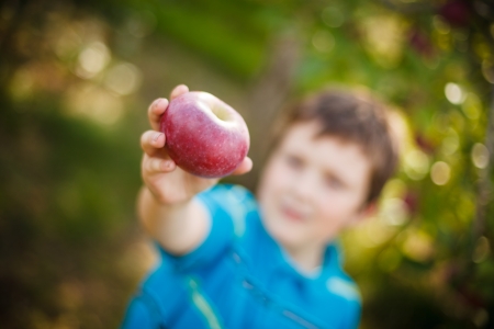 Out of focus boy holding a red appleの写真素材