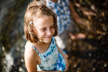 Girl smiling in the sun while having her feet in the waterの写真素材