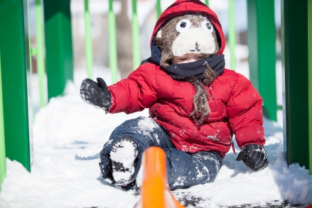 Infant playing on a slider in the snowの写真素材