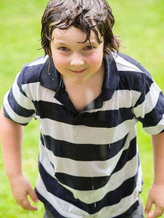 Boy completely wet and playing in the rainの写真素材