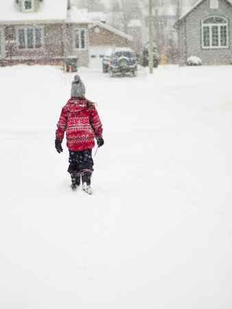 Cute young girl walking in a snow stormの写真素材