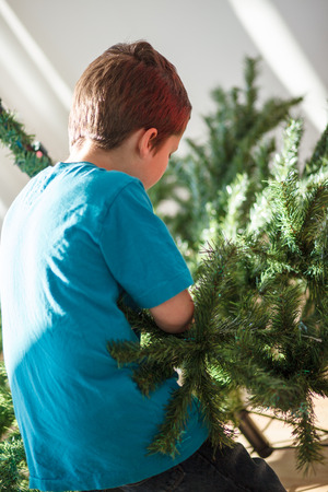 Boy building a Christmas tree inside a houseの写真素材