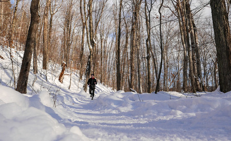 Man trail running in the snow on a beautiful winter dayの写真素材