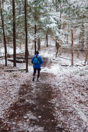 Man running in the snow on a trail in the woodsの写真素材