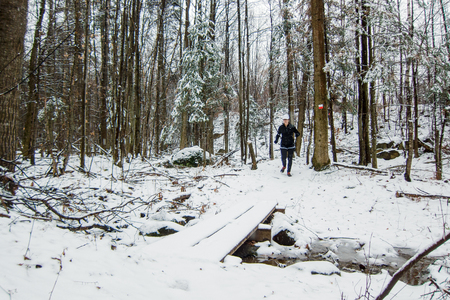Woman running in the snow on a trail in the woodsの写真素材