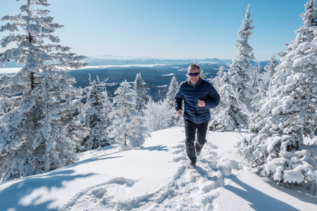Man running in the snow on top of a mountain on a beautiful winter dayの写真素材