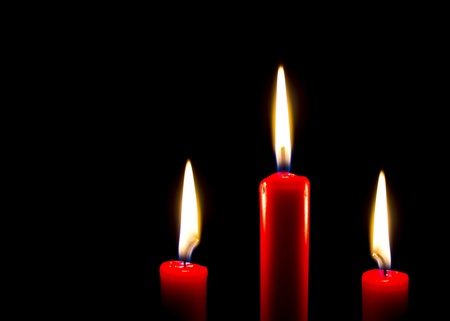 Three red burning candles on a black backgroundの写真素材