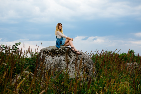 Beautiful girl sits on a rockの写真素材